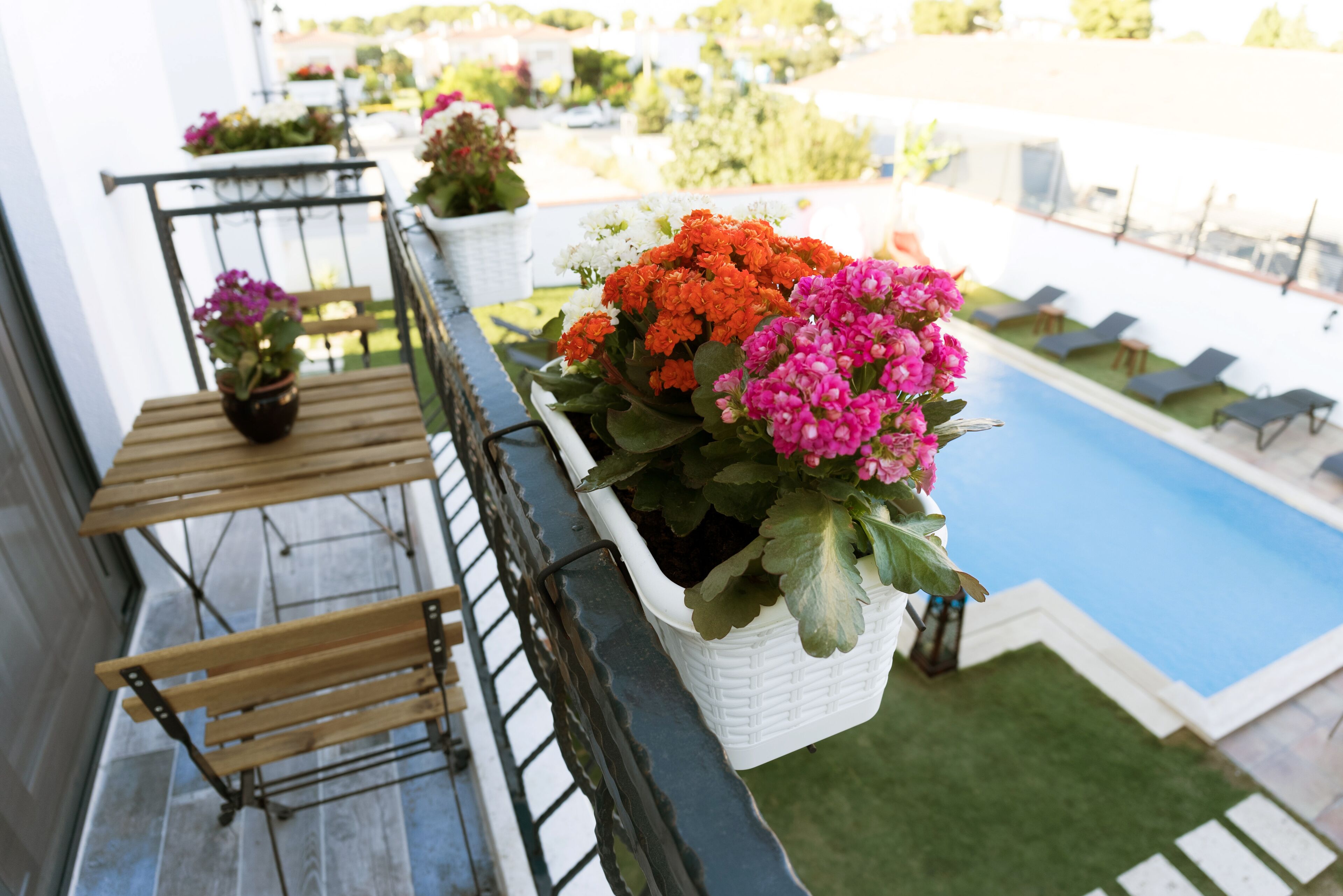 A balcony with potted plants and a pool view.