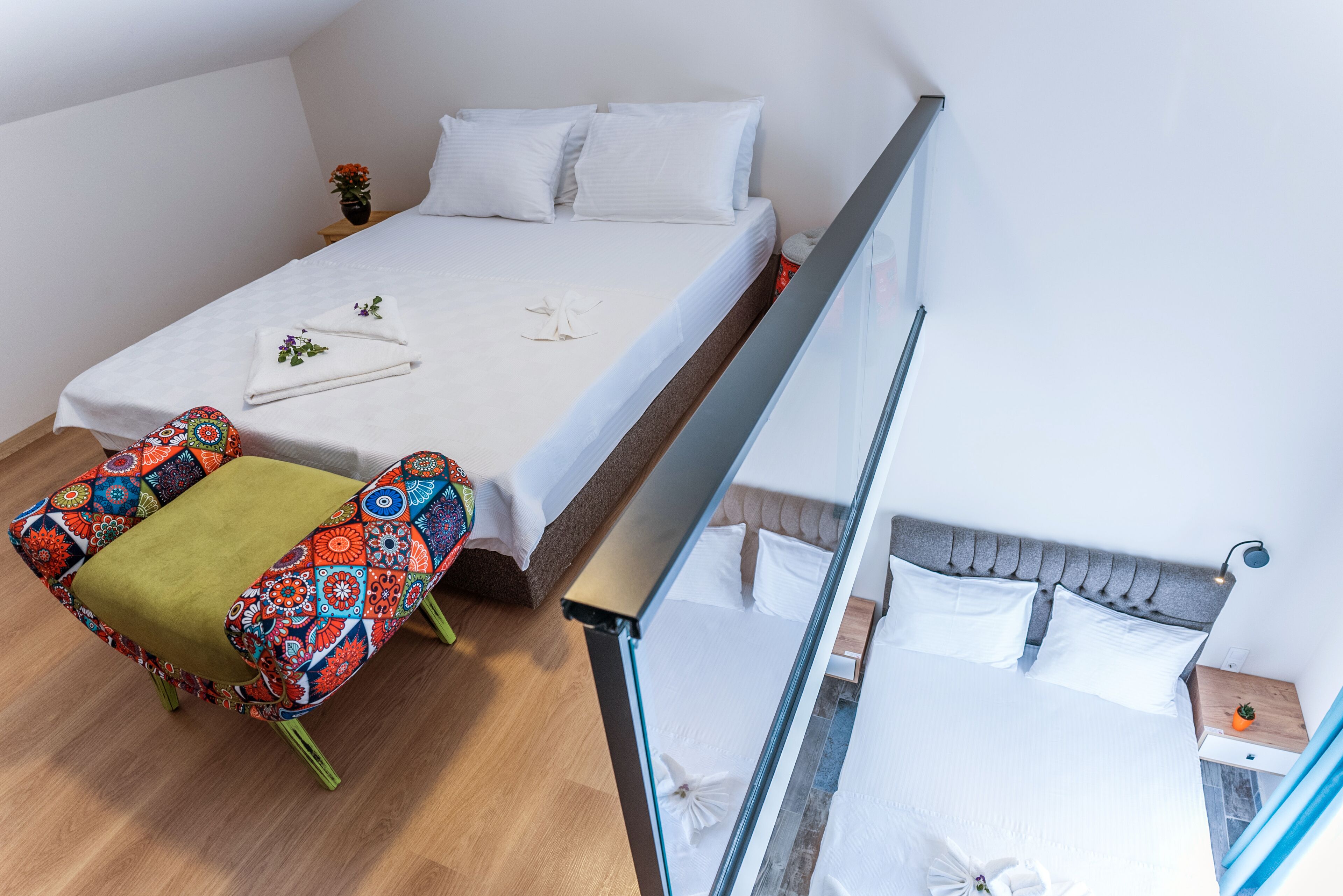 A modern bedroom with a bed, a colorful chair, a small table, and a nightstand.