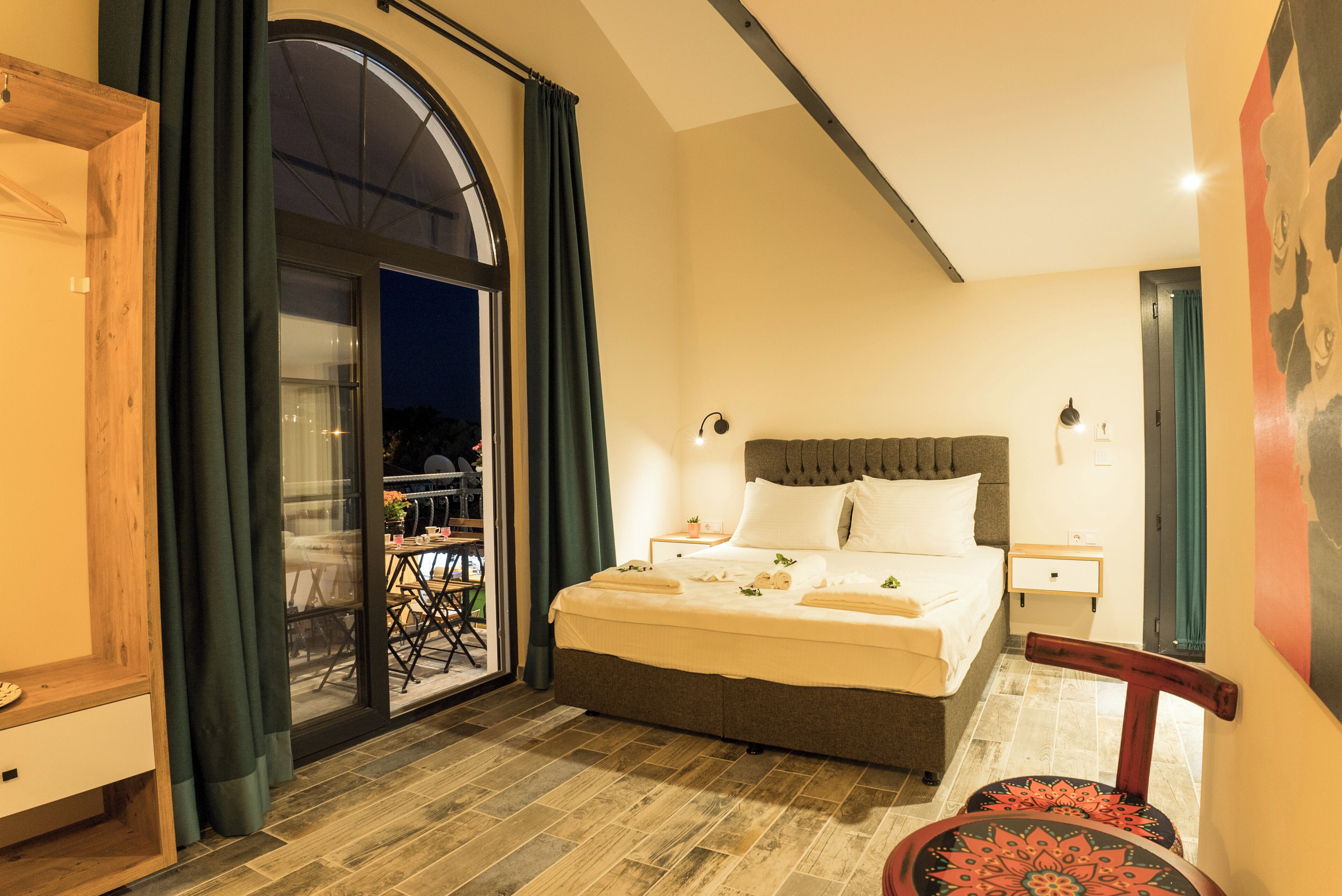 Une chambre d’hôtel avec un grand lit, une table de chevet, une chaise, une fenêtre avec des rideaux et une vue sur l’extérieur.