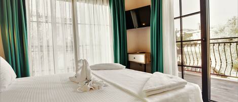 A hotel room with a bed, a TV, a desk, and a balcony.