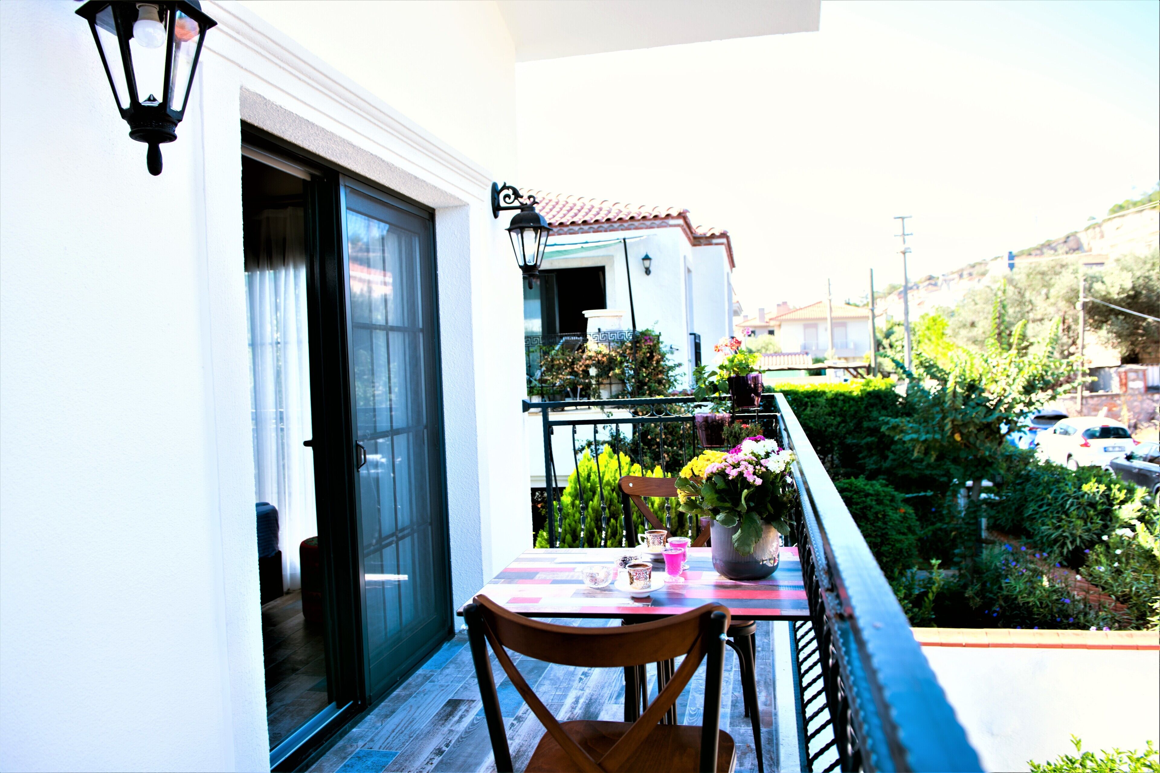 A balcony with a table and chairs, a potted plant, and a view of a residential area.
