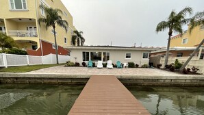 A pool with a wooden deck leading to a building with outdoor seating and palm trees. - Anchors UP #3; WALK to Beach/Bars/Dining (Clearwater Beach)