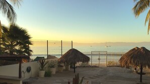 Un espace aménagé au bord de la piscine, avec vue sur la mer, des parasols en chaume et des plantes en pot.