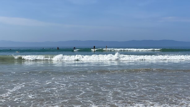 Une plage avec des vagues et des gens qui font de la planche à voile.