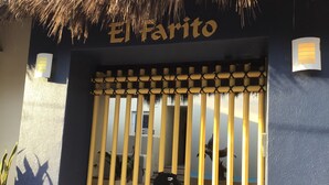 Une entrée d’immeuble avec une enseigne indiquant « El Parito » et une porte en bambou.