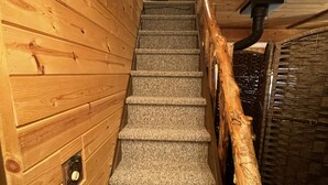 A wooden staircase with carpeted steps and a wooden handrail. - Cozy cabin in Duck Creek (Duck Creek Village)