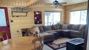 A cozy cabin interior with a wooden dining table, a sofa, and a fireplace. - Cozy cabin in Duck Creek (Duck Creek Village)