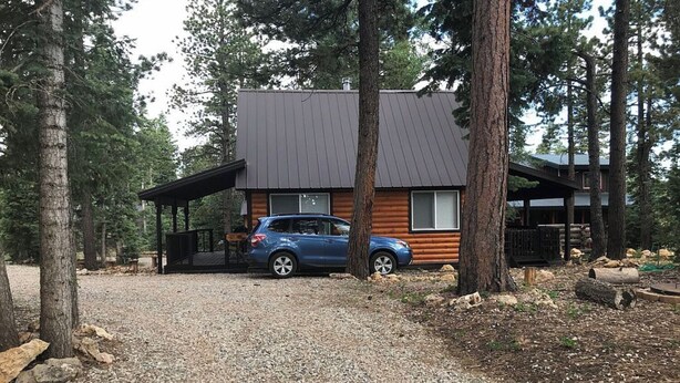 A cabin with a gravel driveway, a covered porch, and a car parked in front. - Cozy cabin in Duck Creek (Duck Creek Village)