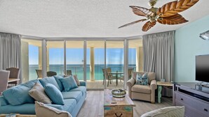 A spacious living room with a large sofa, a coffee table, and a TV. There is a balcony with a view of the ocean. - Long Beach Resort Tower 1 Unit 1303 (Panama City Beach)