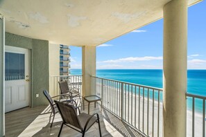 A balcony with a view of the ocean, a door, and a chair.