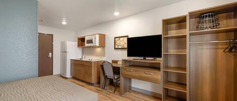 A compact room with a bed, a desk, a television, a microwave, and a wardrobe.