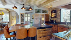 Une cuisine moderne dotée d’un îlot central, de meubles en bois et de luminaires suspendus.