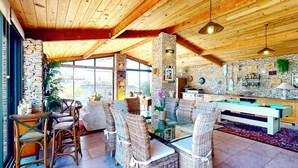 Une pièce chaleureuse, meublée de meubles en osier, avec une table de billard, des murs en pierre et une cheminée en pierre.