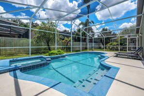 A swimming pool with a glass enclosure, surrounded by a fence and palm trees.