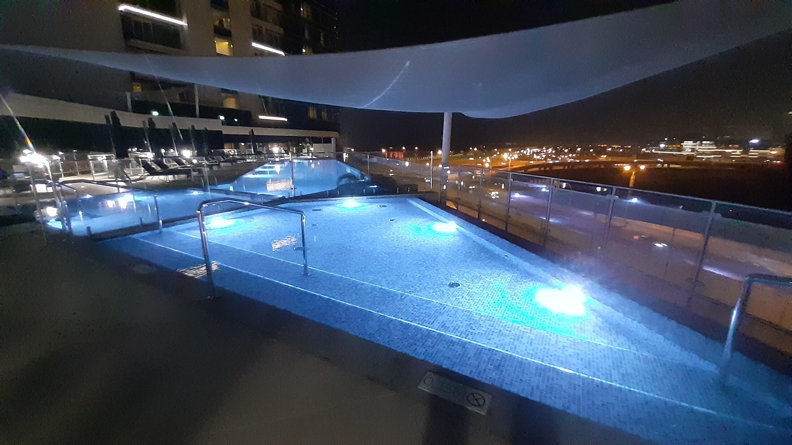 A rooftop pool area with a view of the city at night.