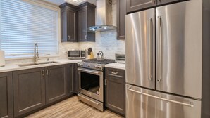 A modern kitchen with dark cabinetry, stainless steel appliances, a built-in oven, and a microwave.