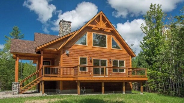 A log cabin with a balcony, a stone chimney, and a large window. - 4bdrm Chalet-close to downtown & outdoor adventure (Bethel)
