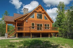 A log cabin with a balcony, a stone chimney, and a large window. - 4bdrm Chalet-close to downtown & outdoor adventure (Bethel)