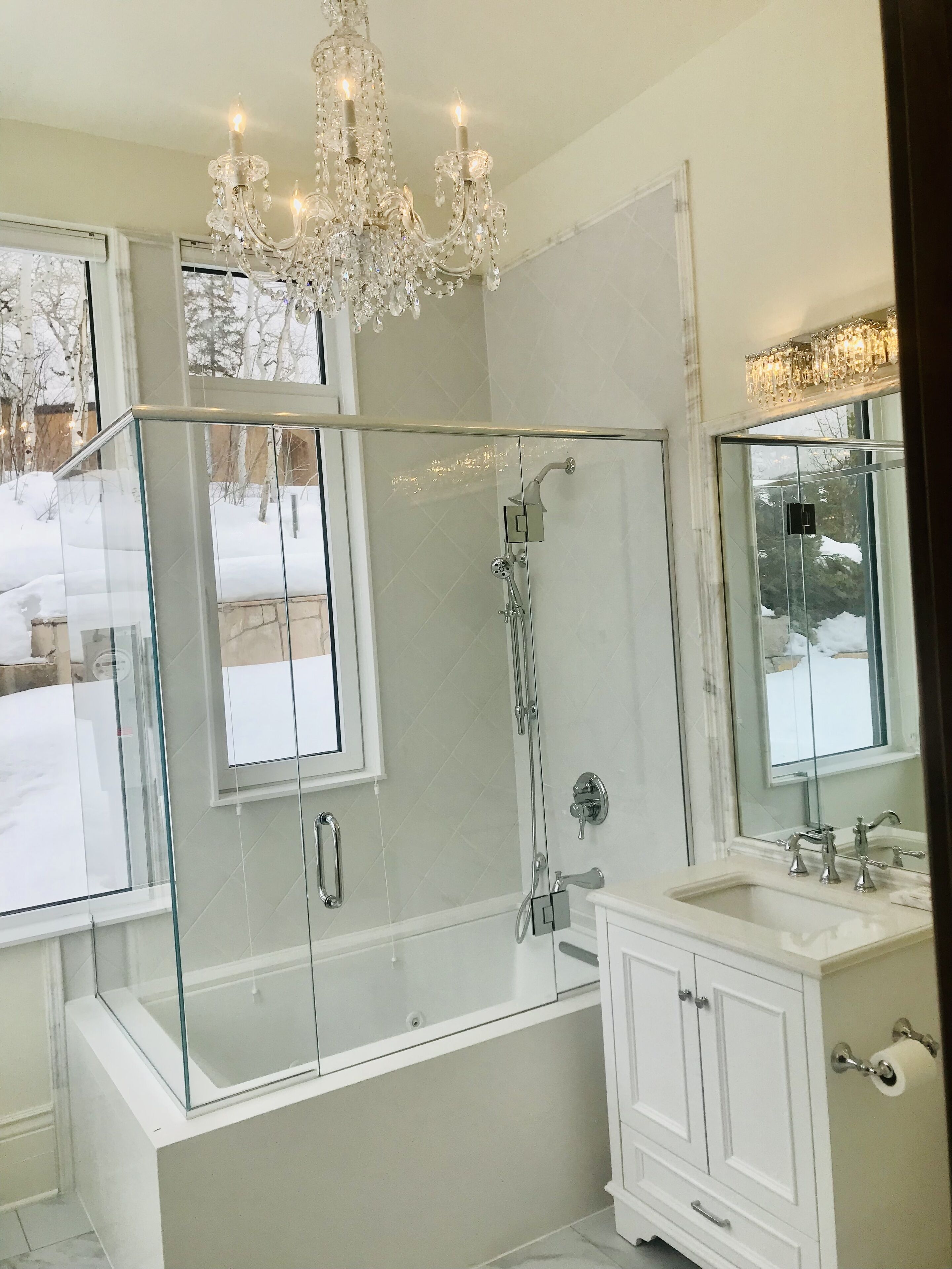 A modern bathroom with a glass-enclosed shower, a freestanding bathtub, and a vanity with a mirror.