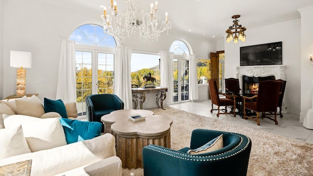 A spacious living room with a fireplace, a chandelier, and a dining area with red chairs. - Exquisite pet friendly home, 5 blks from Gondola with stunning views!! (Aspen)