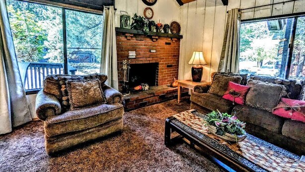 A cozy living room with a fireplace, two sofas, a coffee table, and a clock on the wall.