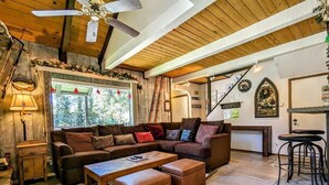 Un salon chaleureux avec un canapé d’angle, une table basse et un coin bar équipé de tabourets.