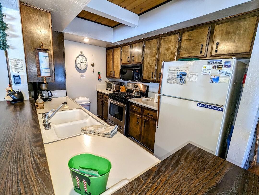 A kitchen with wooden cabinets, a white refrigerator, a stove, and a sink.