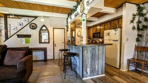 Un intérieur chaleureux avec un plafond en bois, un coin bar et une cuisine dotée de meubles en bois.