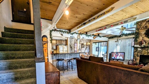 Un coin bar accueillant avec un escalier en bois, des sièges et un téléviseur.