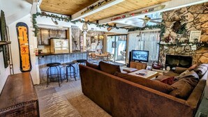 Un salon chaleureux avec un plafond en bois, une cheminée en pierre et un téléviseur.