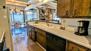 Une cuisine avec des meubles de rangement en bois, un lave-vaisselle, une machine à café et un évier.