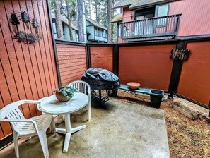 Eine Terrasse mit einem kleinen Tisch und Stühlen, einem Grill und einem Blumentopf.