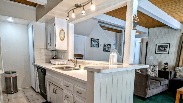 A modern kitchen with white cabinetry, a central island, and a dining area with a sofa and coffee table.