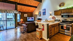 A cozy kitchen with wooden beams, a large window, and a television.