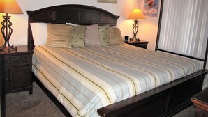 A hotel room with a large bed, two bedside tables with lamps, and two framed pictures on the wall.