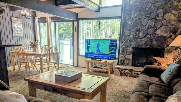 A cozy living room with a stone fireplace, a television, and comfortable seating.