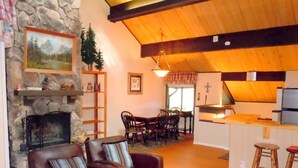 Una sala de estar acogedora con chimenea, comedor y cocina con taburetes.