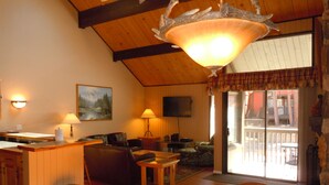 Una sala de estar acogedora con techo de madera, chimenea, televisor y comedor con mesa y sillas.