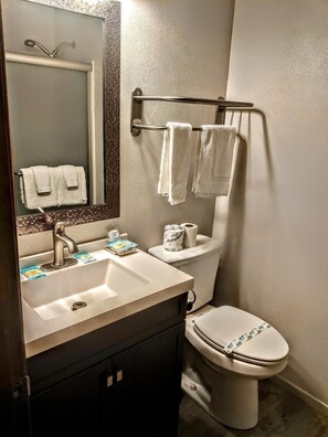A bathroom with a sink, mirror, toilet, and towel rack.