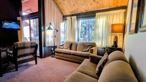 Una sala de estar acogedora con un sofá, una mesa de madera y un televisor.