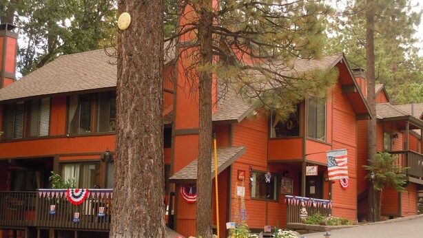 A multi-story building with a red exterior, large windows, and a porch area. There are American flags and patriotic decorations visible.