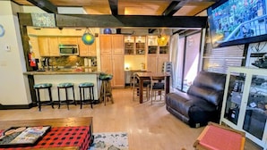 A modern kitchen with wooden cabinets, a microwave, and a dining area with a table and chairs. - Seeking the best location? Ski, Hike, Relax, Repeat in this Cozy Townhouse (Big Bear Lake)