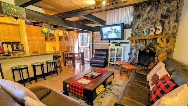 A cozy living room with a fireplace, leather sofas, a coffee table, and a TV mounted on the wall. - Seeking the best location? Ski, Hike, Relax, Repeat in this Cozy Townhouse (Big Bear Lake)