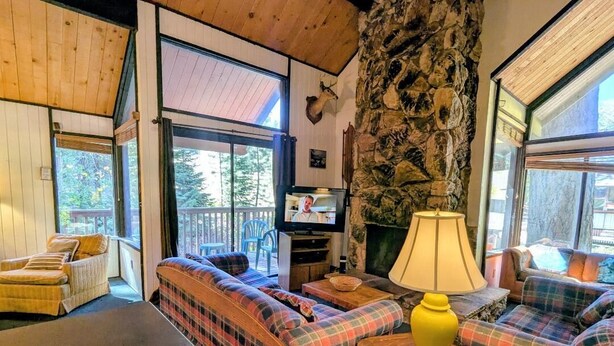 Un salón acogedor con sofás de cuadros, una chimenea de piedra y un televisor.