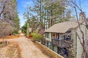 A two-story house with a balcony, a dirt path leading to the house, and a sign indicating a campground nearby.