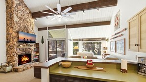 A cozy interior with a stone fireplace, a ceiling fan, and a view of the outdoors.