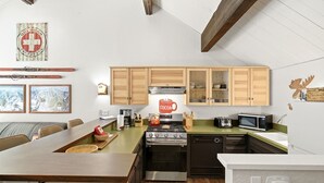A modern kitchen with wooden cabinets, a stove, microwave, and a coffee maker.