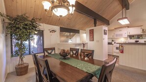 Comedor con mesa de madera, sillas, una lámpara de araña y una planta en maceta.