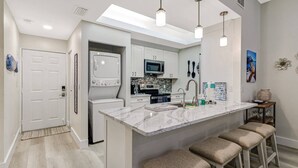Una cocina moderna con una isla central, electrodomésticos integrados y taburetes de bar.
