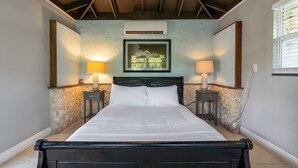 Un dormitorio con una cama, dos mesitas de noche con lámparas, un cuadro en la pared y una ventana con persianas.